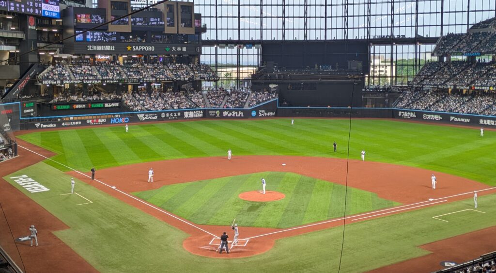 エスコンフィールドHOKKAIDOでのビジター試合風景。打席に立つ選手と守備につくフィールドの様子