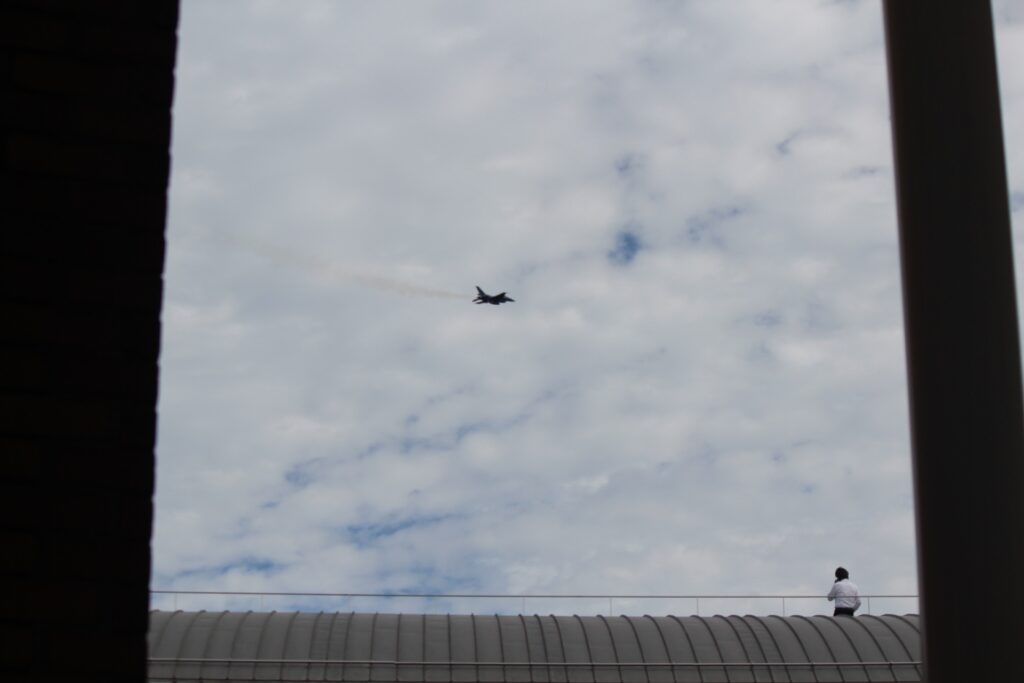 SUPER GT開催日のもてぎ上空を飛行する戦闘機。ウェルカム飛行の演出で会場が盛り上がる様子。