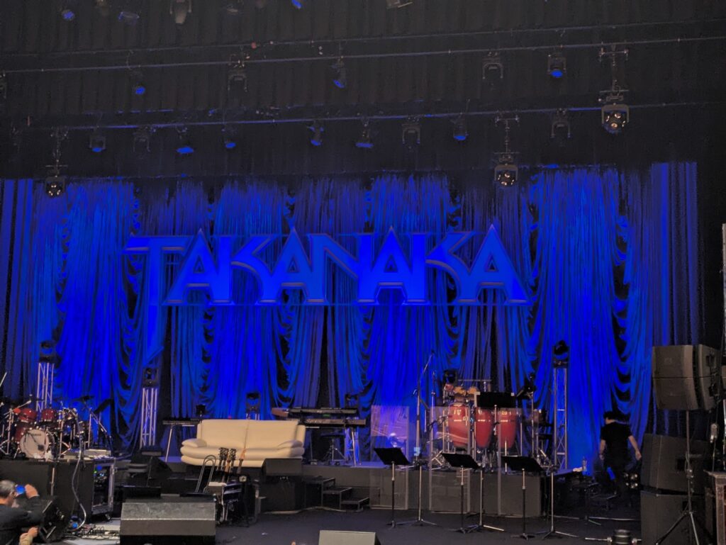 青いライトに照らされたライブステージとTAKANAKAロゴ