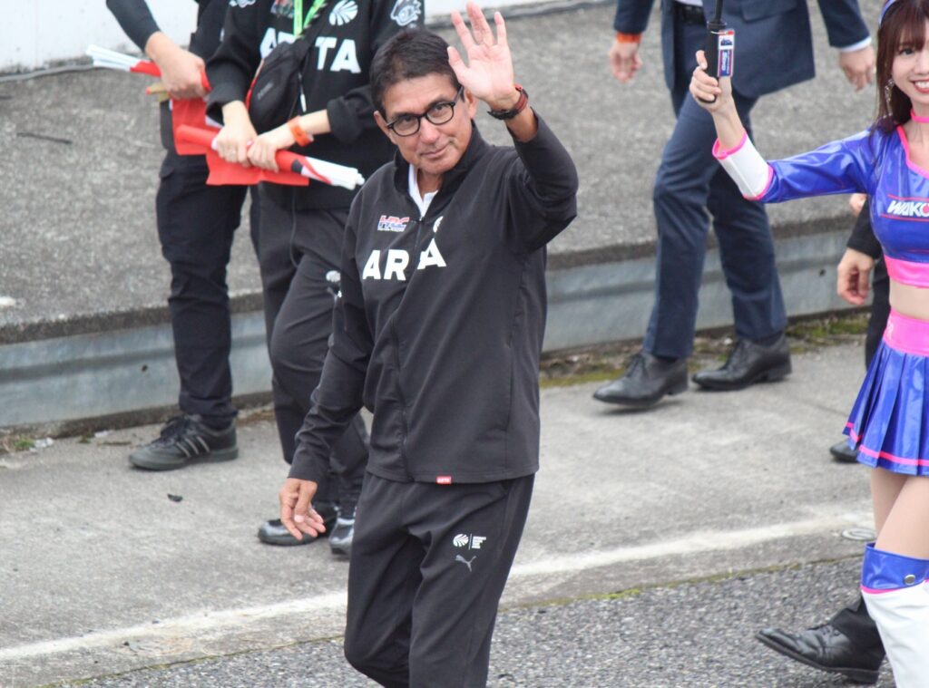 SUPER GTもてぎ2025のピットロードでファンに手を振る鈴木亜久里監督。ARTAチームを率いる姿が印象的。