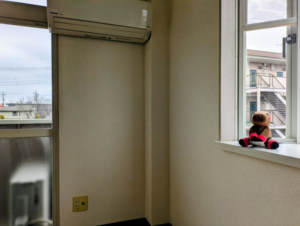 引っ越し前の空っぽの部屋の窓辺に置いたヨシオのぬいぐるみ