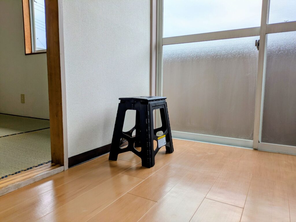 新居のリビングに置かれた黒い折りたたみ脚立とベランダ窓